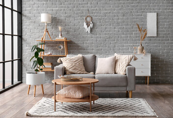 Interior of modern room with sofa, table and dream catcher on brick wall