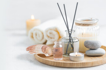 Concept of spa treatment in salon. Natural organic oil, towel, candles as decor. Atmosphere of relax, serenity and pleasure. Anti-stress and detox procedure. Luxury lifestyle. White wooden background