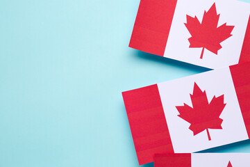 Paper flags of Canada on blue background, closeup