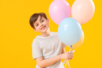 Fototapeta na wymiar Little boy with balloons on yellow background. Children's Day celebration