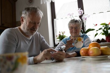 85 years old grey haired grandmother drink a tee in the kitchen with her son 