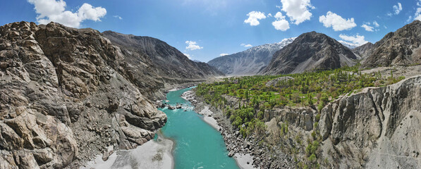 A 180-degree aerial panorama of a valley and a flowing river of green glacial water, located between the surrounding mountains. 