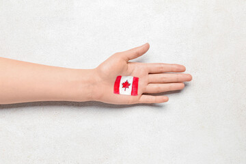 Female hand with drawn flag of Canada on white background