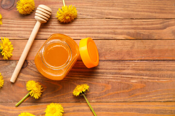 Jar with dandelion honey on wooden background