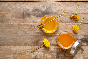 Jar and bowl with dandelion honey on wooden background
