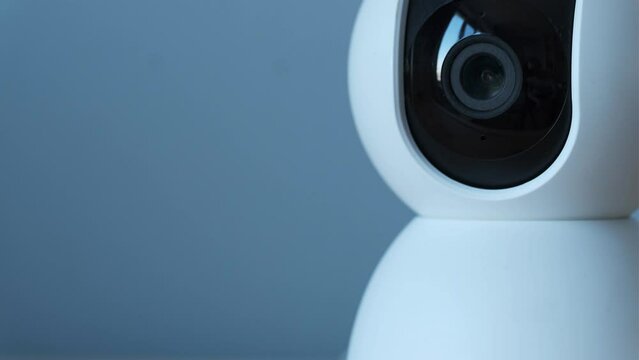 Macro shot of home surveillance camera.  Security camera lens moving while scanning the room. Safety and theft protection concept