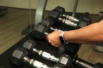 Dark-haired latino adult man exercises in a gym, muscle strength work for physiotherapy rehabilitation on arm with dumbbells