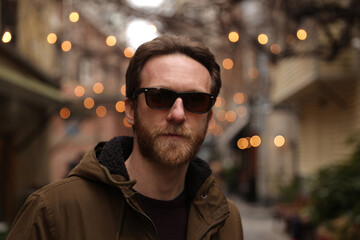 Bearded caucasian man with sunglasses posing in cafe street for a photo with bokeh