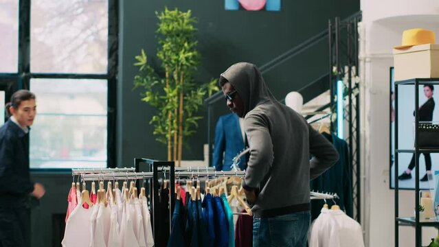 African american robber trying to sneak stolen shirt being caught by store security guard in modern boutique. Bodyguard asking thief to return stylish merchandise or will call the police Generative AI