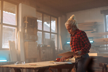 Woman designing products in wood workshop.