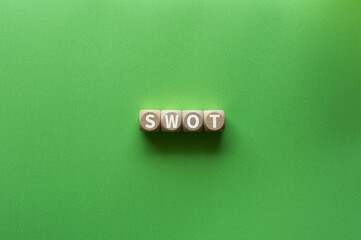 There is wood cube with the word SWOT. It is an abbreviation for strengths, weaknesses,...