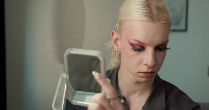 Transgender guy applying make up on eyes using a brush