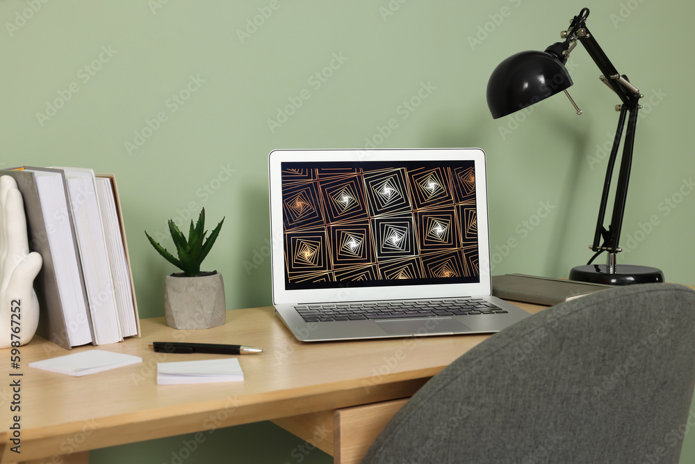 Sticker Modern laptop, books, lamp and stationery on wooden desk near green wall. Home office