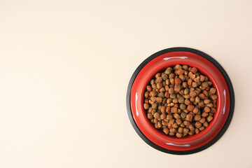 Dry dog food in feeding bowl on beige background, top view. Space for text