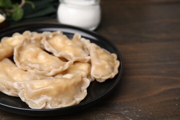 Plate of delicious dumplings (varenyky) with cottage cheese on wooden table, closeup