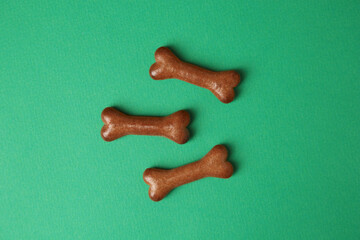 Bone shaped dog cookies on green background, flat lay
