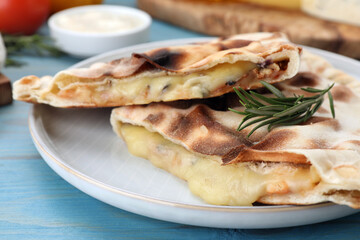 Tasty pizza calzones with cheese and rosemary on light blue wooden table, closeup