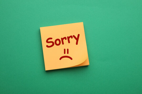 Apology. Sticky note with word Sorry and drawn sad face on green background, top view