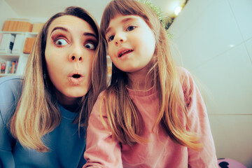 Mother and Little Toddler Girl Trying to Take Silly Selfies. Mom her daughter playing with a camera
 - obrazy, fototapety, plakaty
