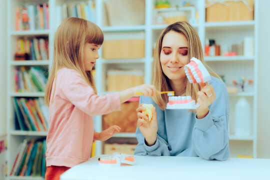Girl Learning about Dental Hygiene Using a Brush and Teeth Model. Happy mother explaining her little girl about proper brushing 
