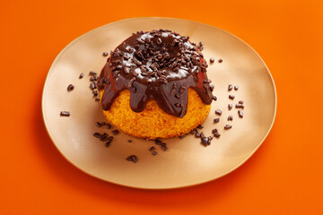 Mini volcano carrot cake with chocolate topping and chocolate sprinkles on orange background