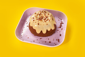 Chocolate vulcan cake with chocolate shavings on pink plate on yellow background