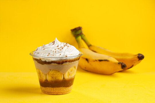 Banoffee pie in a dessert cup (brazilian copo da felicidade - banof, banofe) with banana yellow background