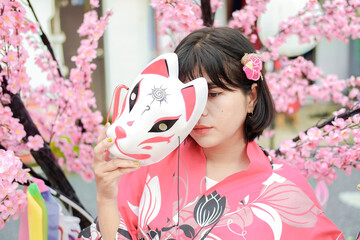 Photo of a young woman wearing a kimono against a backdrop of cherry blossoms