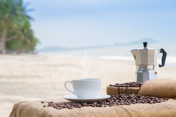 Fototapeta Close-up white coffee cup and many coffee beans placed around on the wood table with a beautiful seascape of nature background, concept coffee vacation travel. obraz