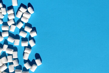 Background of many marshmallows of different sizes on a blue background with space for text.