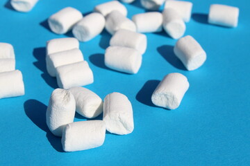 Fototapeta na wymiar Background of many marshmallows of different sizes on a blue background with space for text.