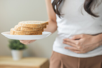 Gluten allergy, asian young woman hand holding, refusing to eat white bread slice on plate in...