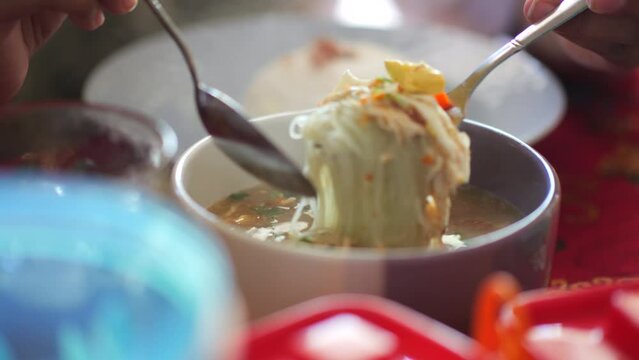 Person eating banjarese soup for dinner on the table. Soto banjar is a soto made from chicken meat as its main ingredient, then added with various spices such as onion, white onion, cumin, fennel.