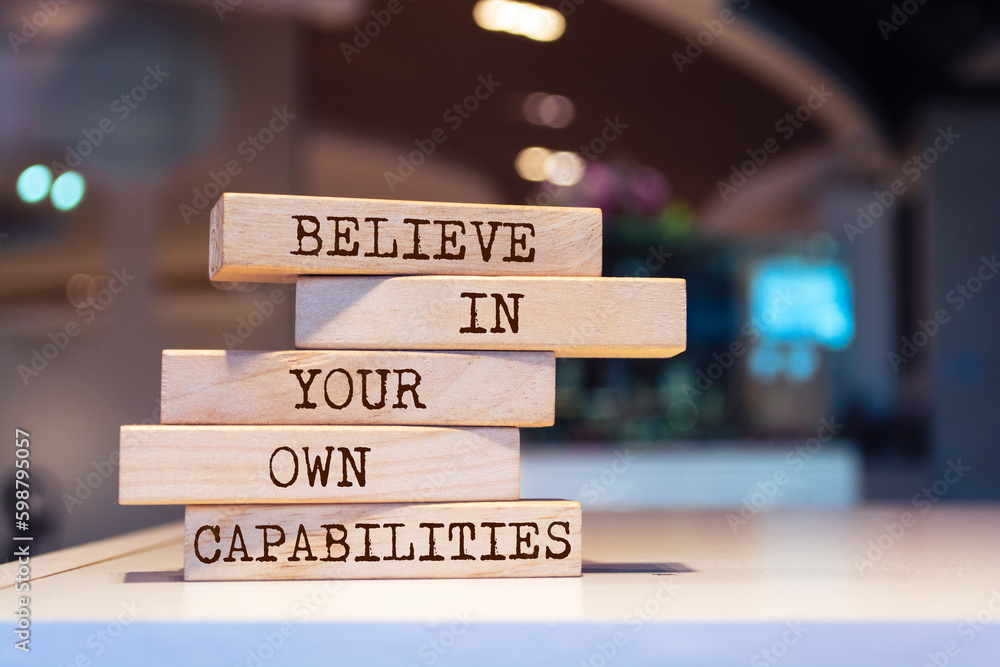 Wall mural wooden blocks with words 'believe in your own capabilities'.