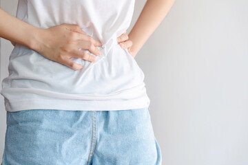 Woman in white shirt holding her stomach because of pain. Health care concept.