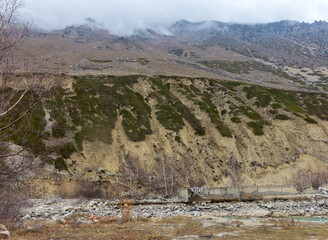 Panorama of mountainous terrain and peaks with low clouds, weather conditions before rain.