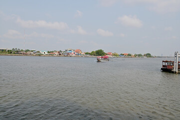 Fototapeta na wymiar BANGKOK, THAILAND - May 11, 2023 : Wooden houses, Thai houses and buildings along the Chao Phraya River with white clouds and blue sky background, Town Bangkok Waterfront, Thailand.