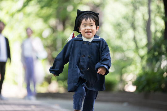 子どもを見守る両親とかわいい園児　走る子供　お受験など通学のイメージに　コピースペースあり