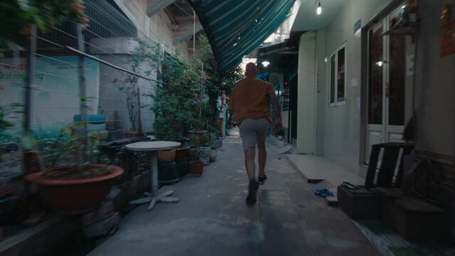 Professional parkourist in sportswear running along cozy narrow street in old town and performing side flip stunt. Back shot