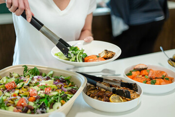 close up of women woman person serving food salads chicken fish buffet at a company meeting dinner lunch luncheon close up hands potatoes dressing