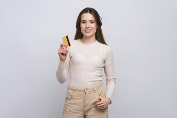 Beautiful confident Caucasian young woman in casual clothes, showing at camera a golden credit card