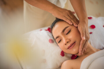 Beautiful asian client lay comfortably on the spa bed with closed eyes after get massage by professional masseuse.