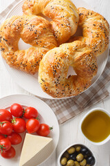 Acma Turkish Style Soft Bagels served with tomato, cheese, olive and olive oil closeup on the plate on the table. Vertical top view from above