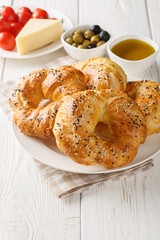 Acma Turkish Style Soft Bagels served with tomato, cheese, olive and olive oil closeup on the plate on the table. Vertical