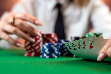 woman's hand on a pile of poker chips at a round poker table.