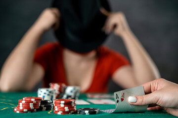 beautiful young girl is sitting at a poker table with cards in her hands. poker game of chance