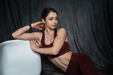 young slim woman in red sport cloth bra posign near chair isolated on black