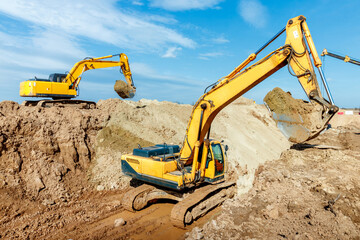 Two Excavator are digging soil in the construction site on sky background,with white fluffy cloud