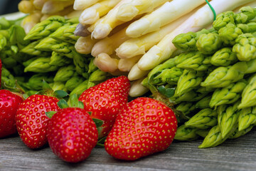 Grüne Spargel, weiße Spargel und frische Erdbeeren dekoriert auf einem rustikalen Holztisch