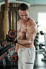 Fototapeta na wymiar Fit strong man doing exercise with dumbbells to pump muscles